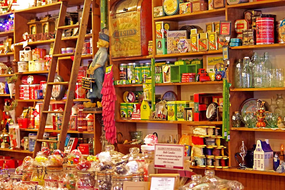 A cluttered shop with shelves full of jars, tins, and glass bottles.