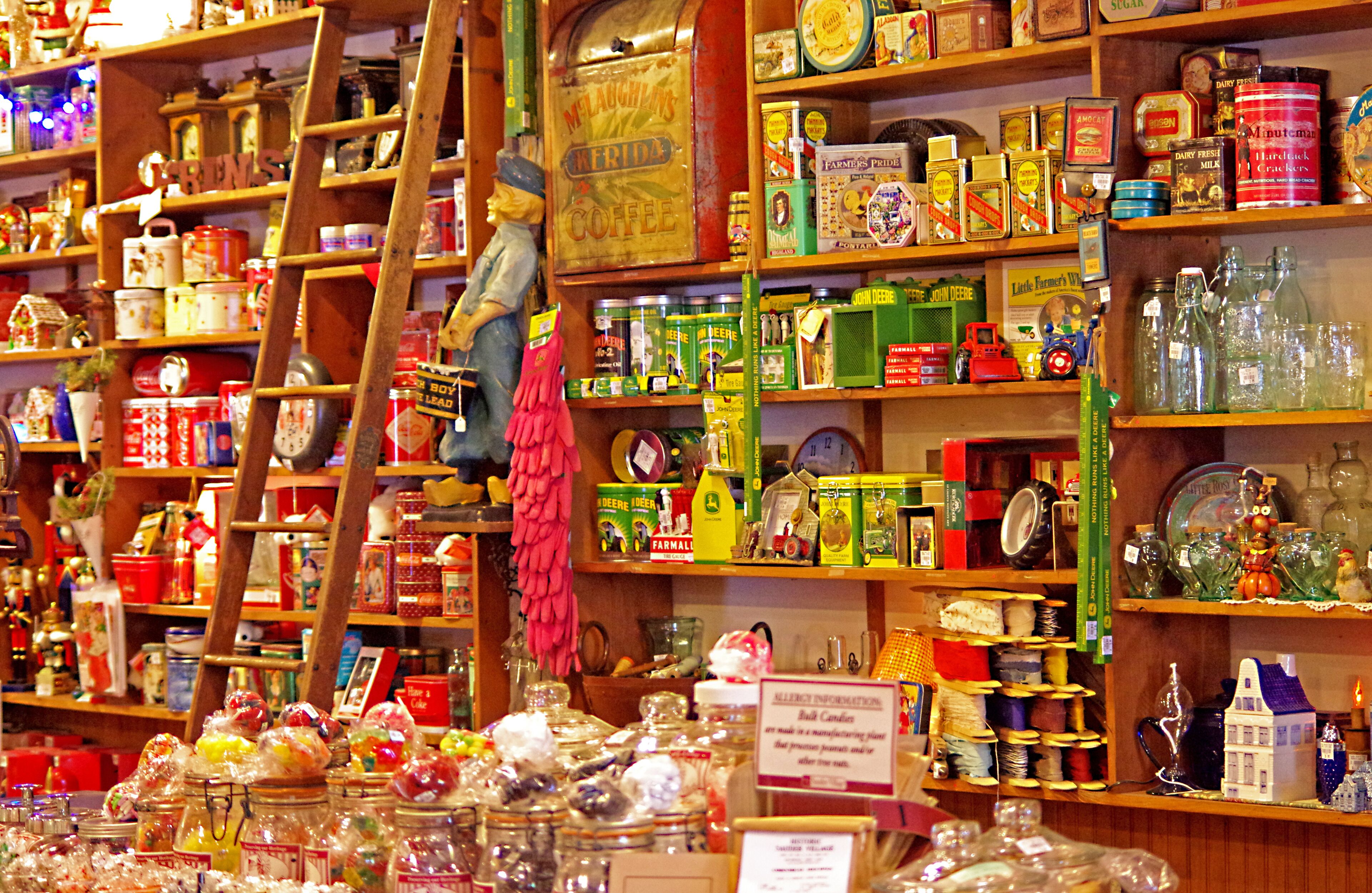 A cluttered shop with shelves full of jars, tins, and glass bottles.