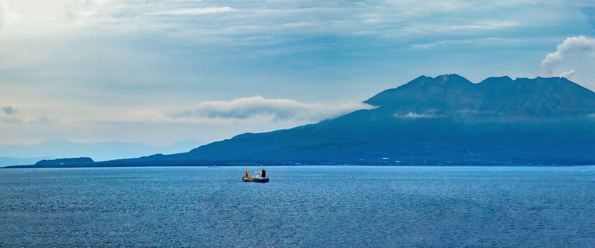 A mountain range with a ship in the foreground.