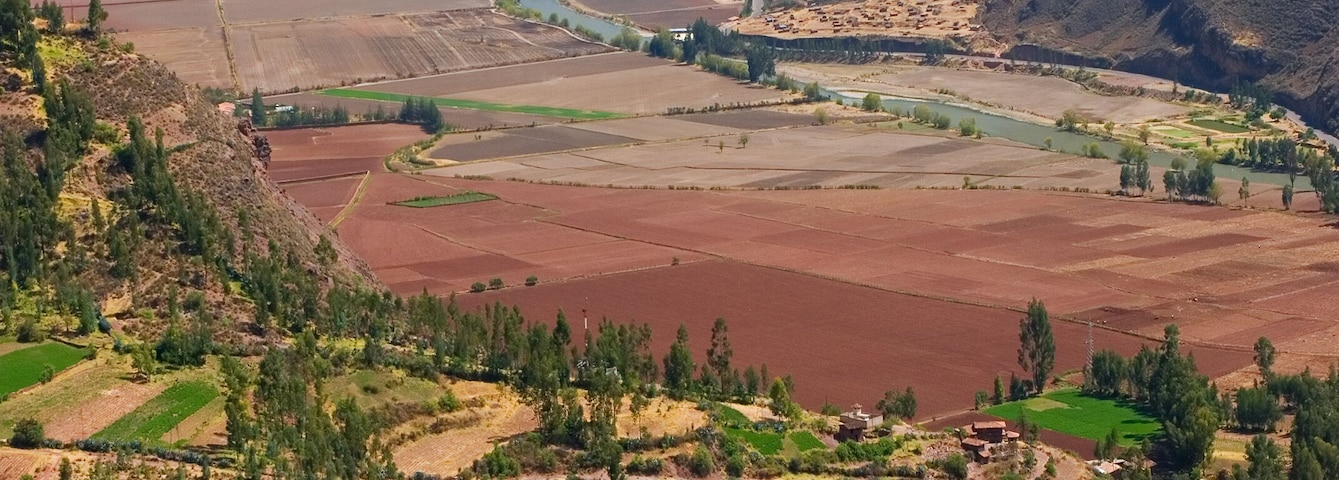 Paisagem montanhosa com campos em terraços, um rio e uma pequena aldeia.