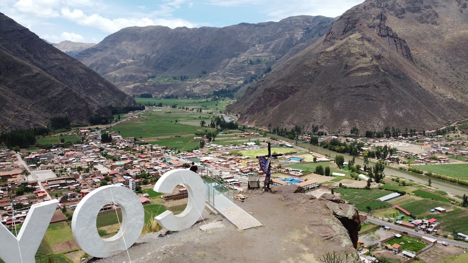 A mountainous landscape with a valley, a river, and a town with colorful buildings.