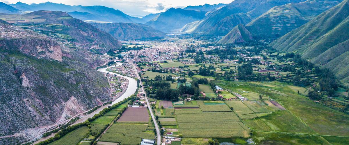 A mountainous landscape with a river, fields, and a town nestled between the hills.