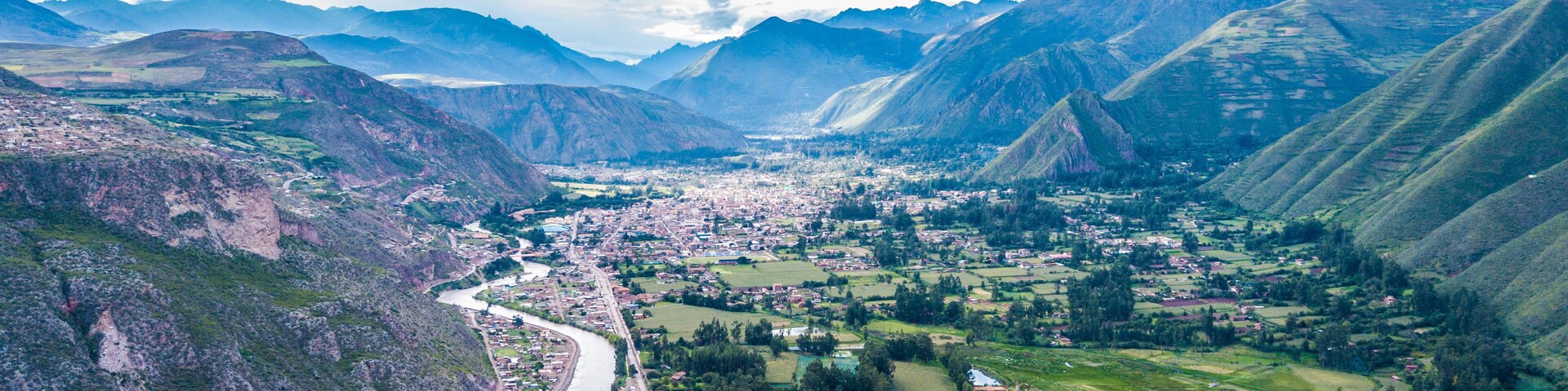 A mountainous landscape with a river, fields, and a town nestled between the hills.