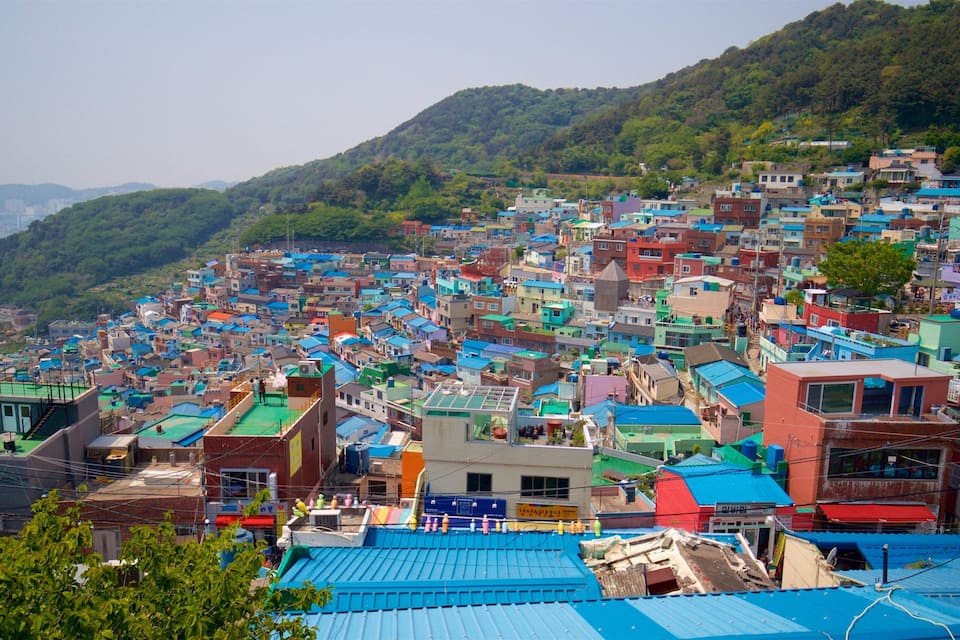 A densely packed hillside town with colorful buildings and lush green hills in the background.