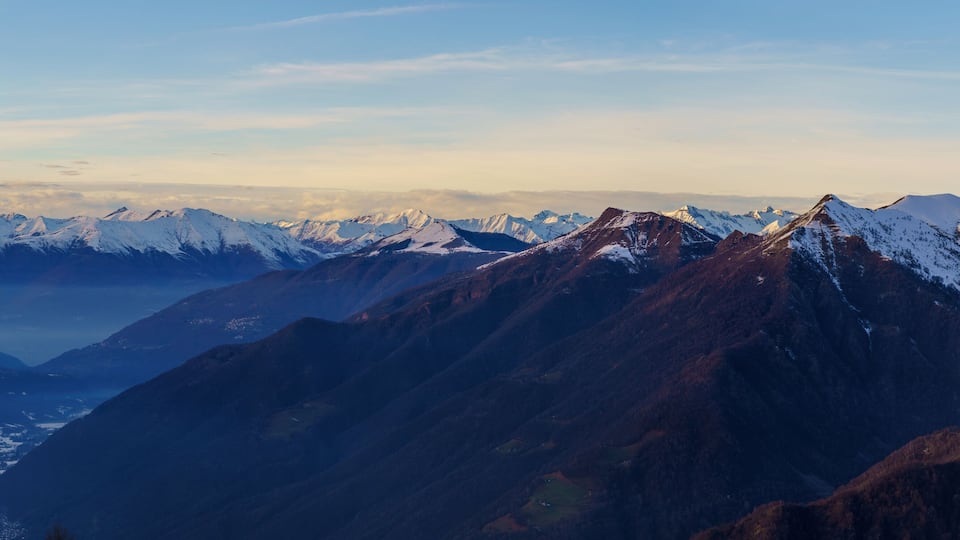 A mountain range with snow-capped peaks and a valley below.