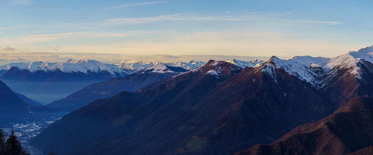 A mountain range with snow-capped peaks and a valley below.