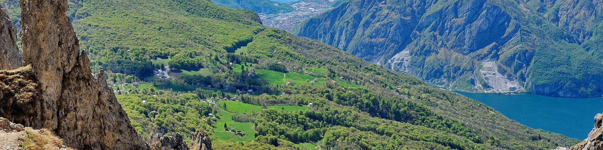 A mountainous landscape with a valley, a lake, and a prominent rock formation.