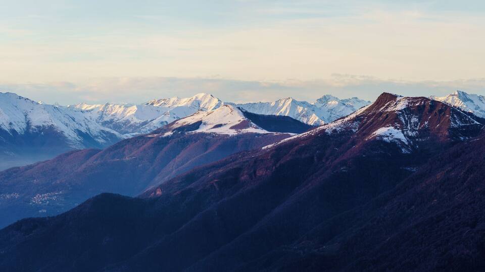 A mountain range with snow-covered peaks and a valley below.