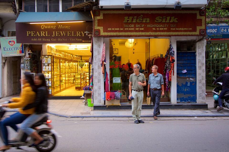 A street with shops, including a pearl jewelry store and a tailor shop.