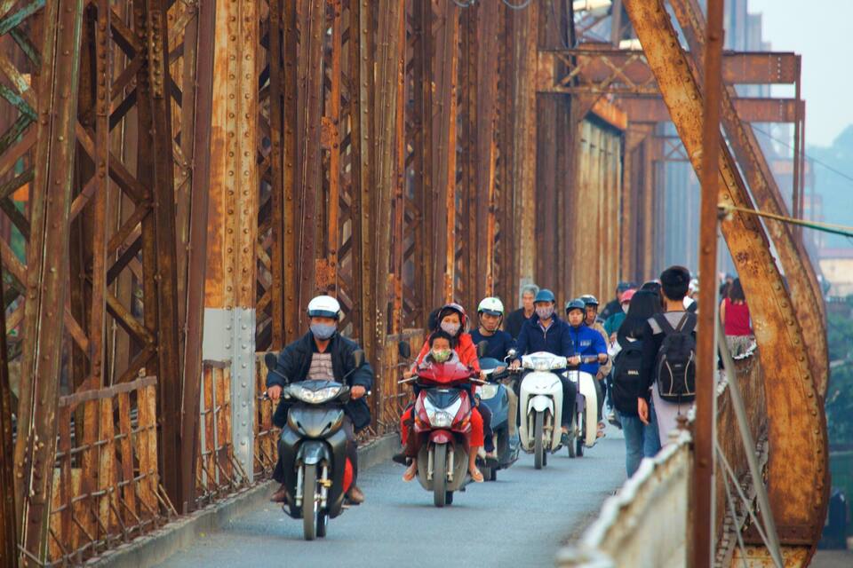 Un grupo de motociclistas sobre un puente oxidado con barandillas metálicas y una pasarela de concreto.