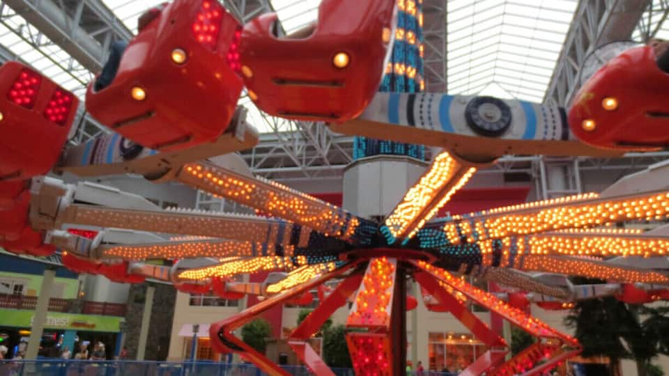 A brightly lit amusement ride with multiple seats and a central rotating structure.