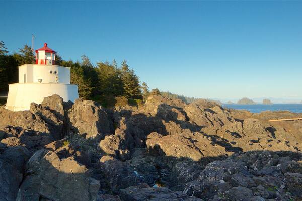 Amphitrite Point Lighthouse featuring a lighthouse, a sunset and rugged coastline