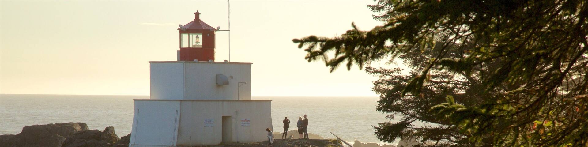 Amphitrite Point Lighthouse som omfatter barsk kystlinje, et fyrtårn og udsigt over kystområde