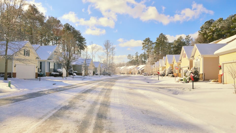 The morning after a frigid snow storm went through this retirement community, icy streets and a cold sky with rows of houses and christmas decorations