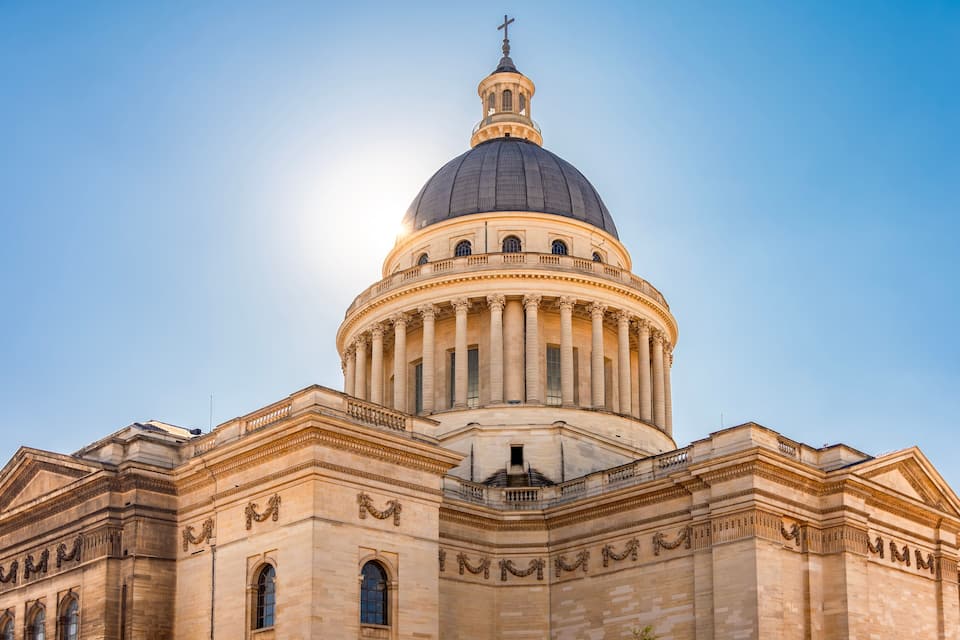 A large domed building with a cross on top, featuring classical architecture with columns and arched windows.