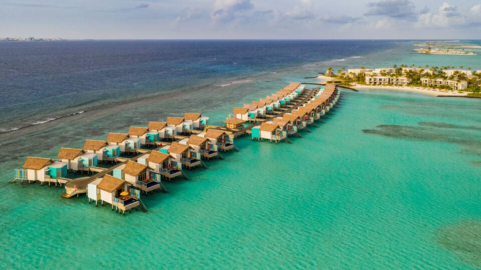 An overwater bungalow resort with turquoise waters and a clear sky.