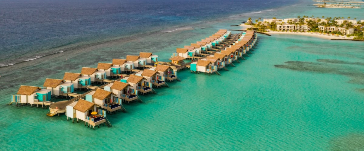 An overwater bungalow resort with turquoise waters and a clear sky.
