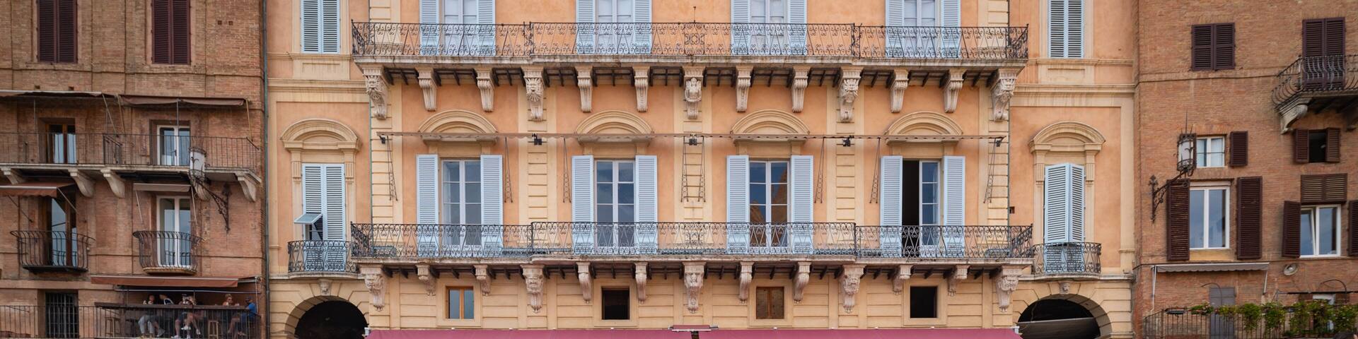 Un bâtiment historique doté de balcons richement décorés et d’une fontaine ornée de statues.