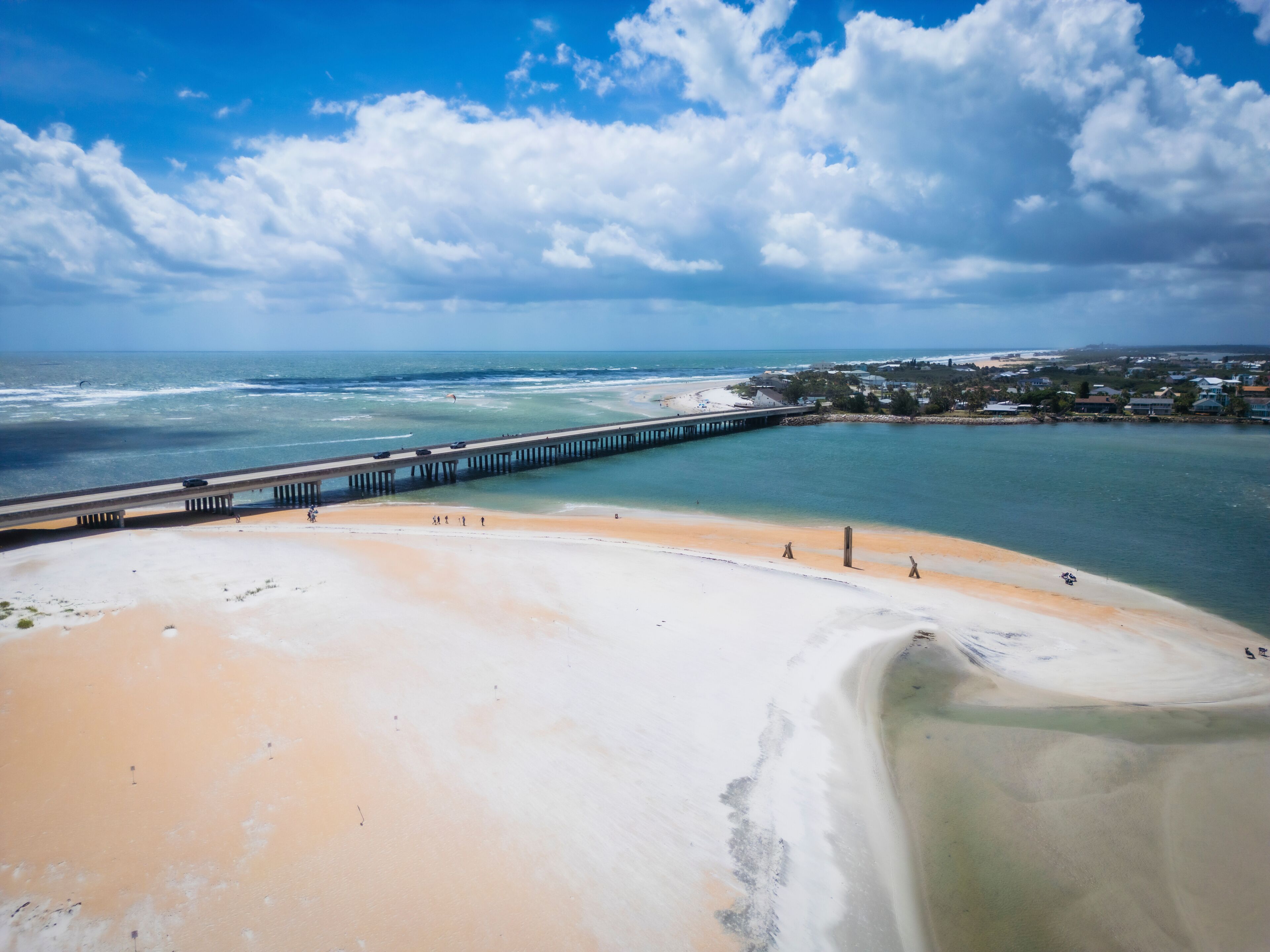 Aerial view of serene crescent beach with people at low tide and vibrant colors, St. Augustine, United States.