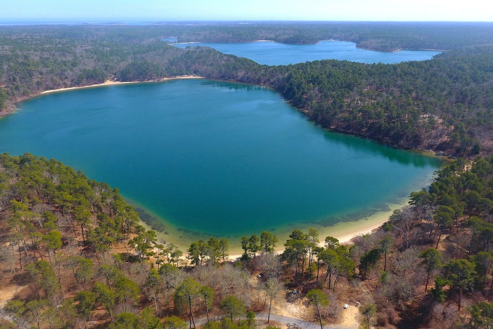 Suuri, turkoosinsininen järvi, jonka ympärillä on tiheää metsää ja jonka rannalla on hiekkaranta.