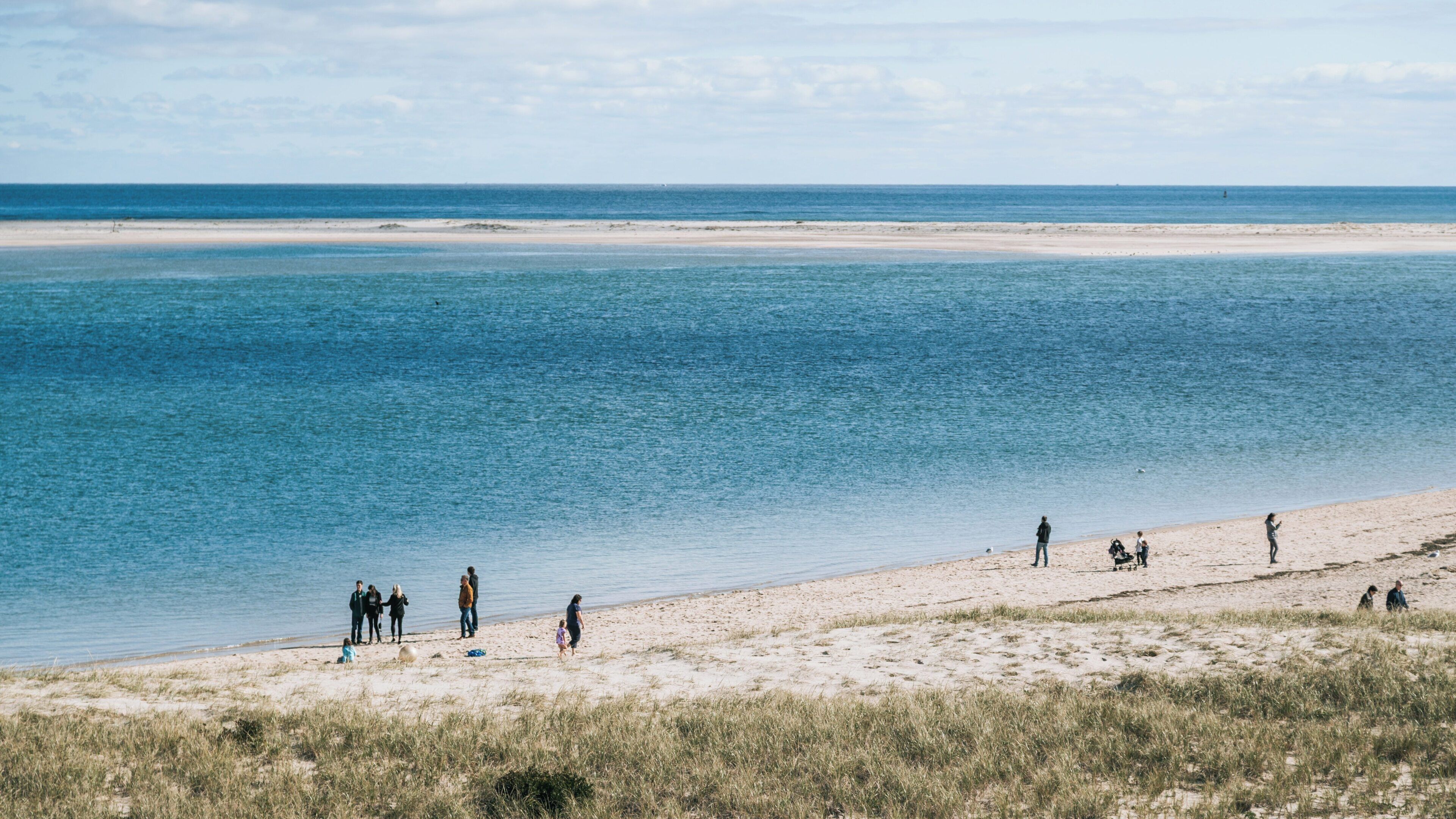 Visitors enjoy a sunny day at Chatham Lighthouse Beach in Massachusetts, experiencing the tranquil ocean views and sandy shoreline