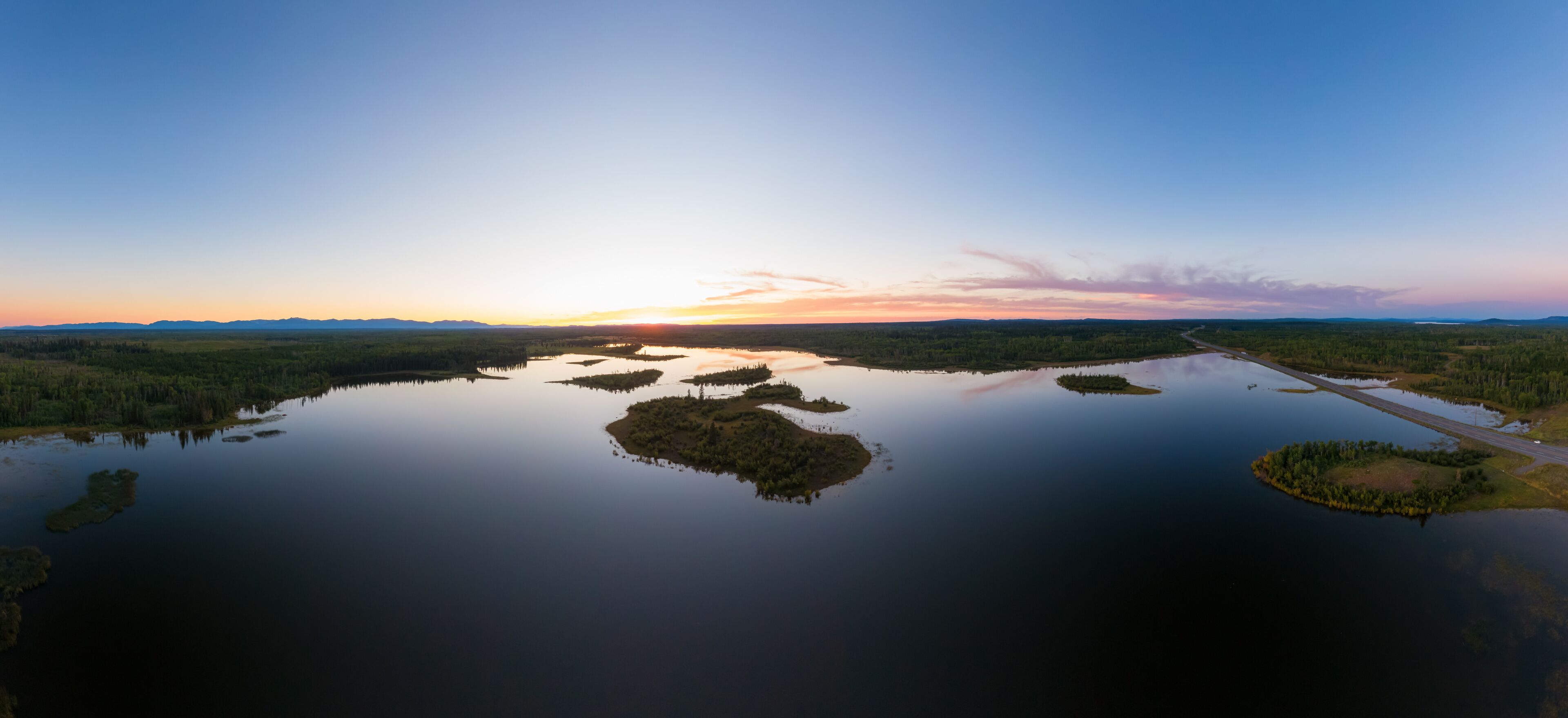 Picturesque Aerial View of Canadian Scenic Island surrounded by Peaceful Lakes. Vibrant summer sunset on the horizon. Cariboo Highway, Interior British Columbia.