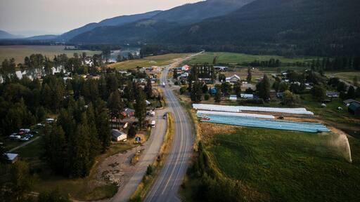 Aerial view of scenic mountains and lush fields with a peaceful road winding through, Little Fort, Canada.