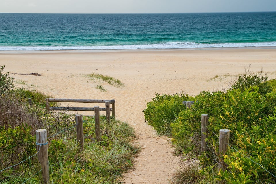 A sandy beach with a wooden pathway leading to the ocean.