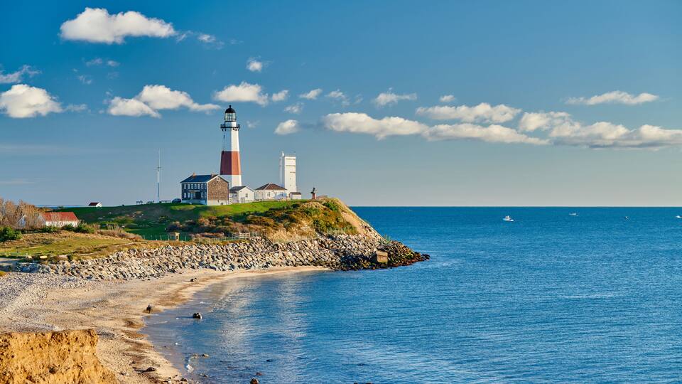 A lighthouse on a rocky coastline with a clear sky.