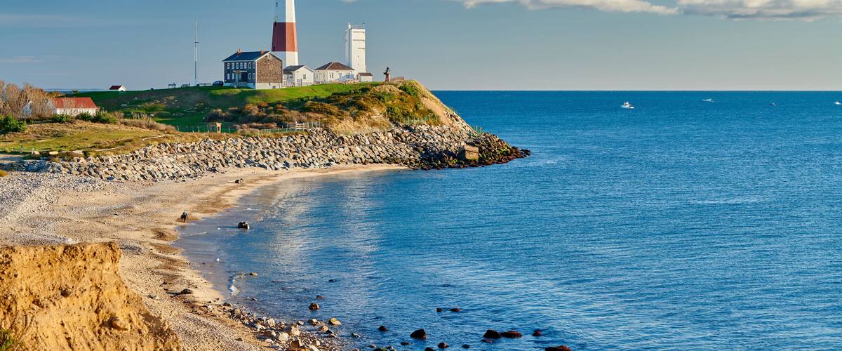 A lighthouse on a rocky coastline with a clear sky.