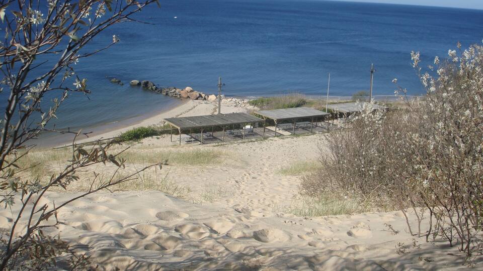 A sandy beach with a wooden structure and a clear view of the ocean.