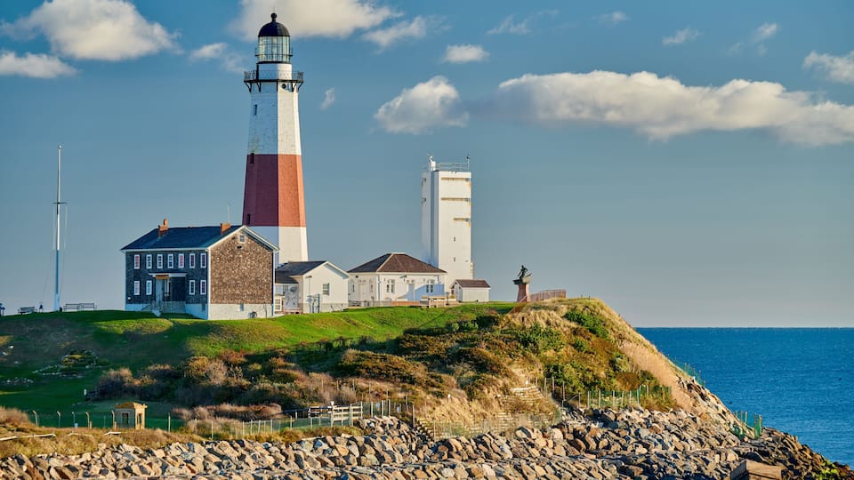 A lighthouse, a white building, and a rocky shoreline.