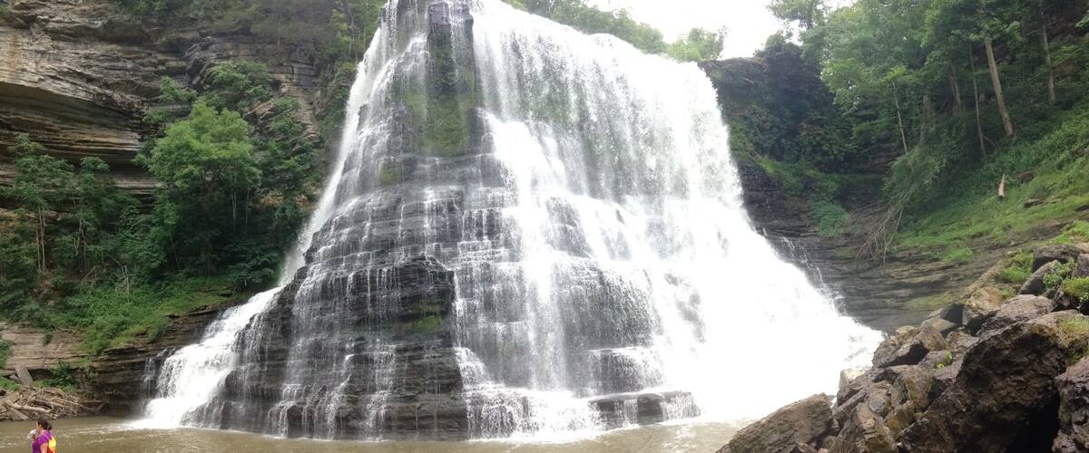 A large waterfall cascading down a rocky cliff surrounded by lush greenery.