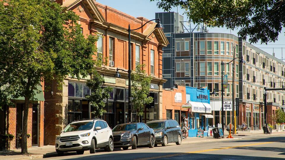A street lined with brick buildings, parked cars, and a modern building with a curved facade.