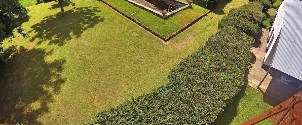 A well-maintained garden with a central lawn, a stone structure, and surrounding trees.