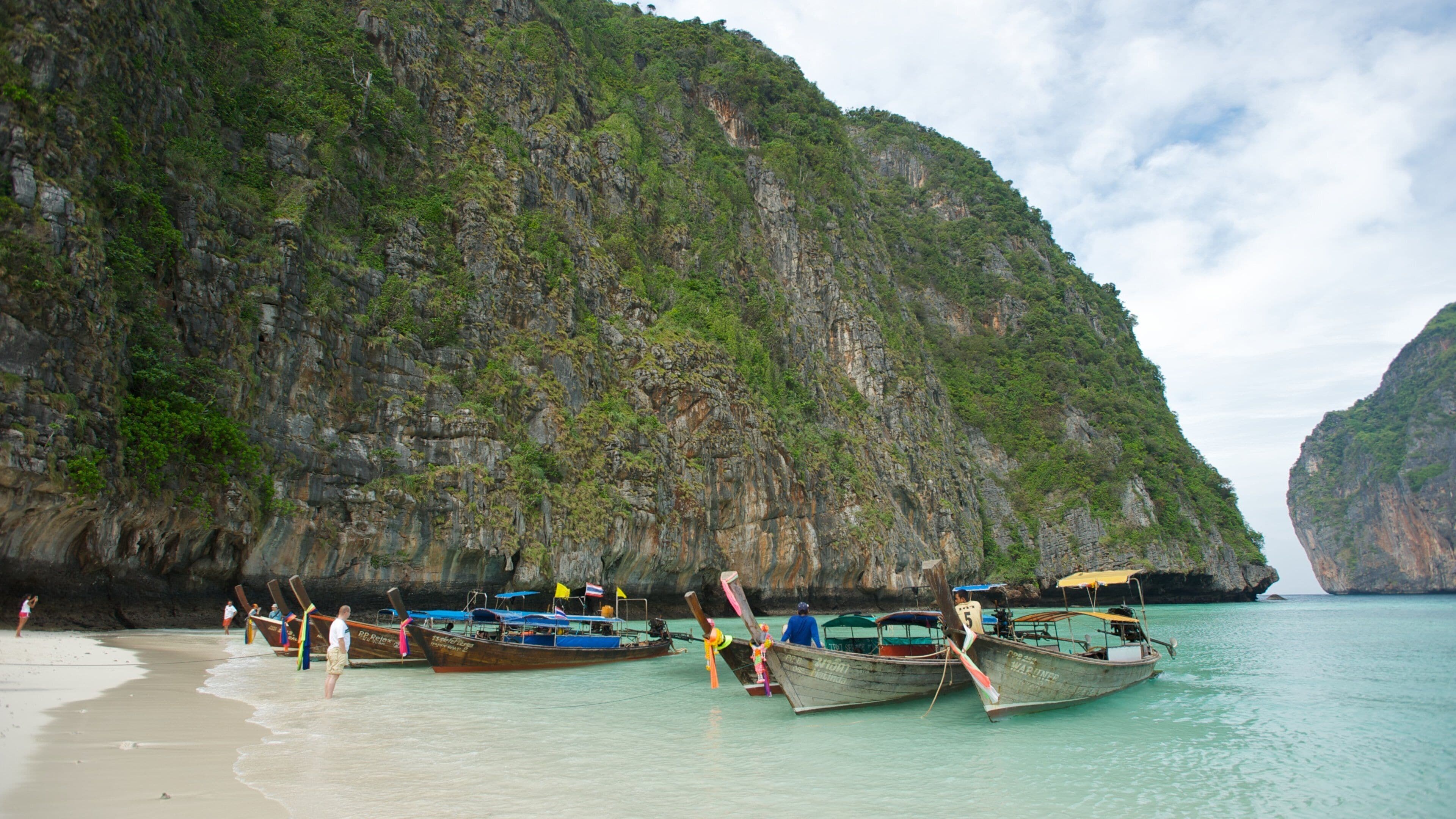 A beach with boats and people.