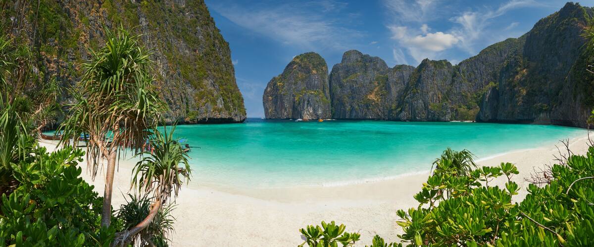 A beach with clear turquoise water, white sand, and limestone cliffs.