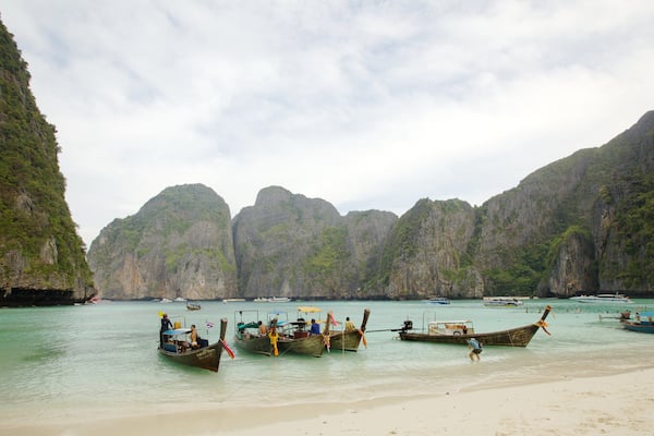 Une plage avec des bateaux et des falaises rocheuses.