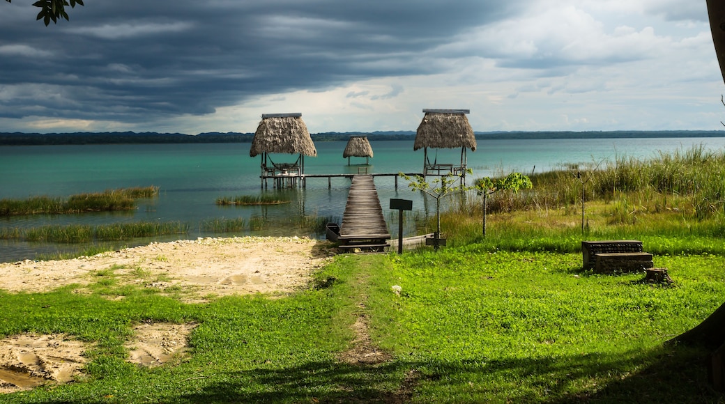 Hammocks on dock along the lake shore with dark blue cloudscape, El Remate, Peten, Guatemala