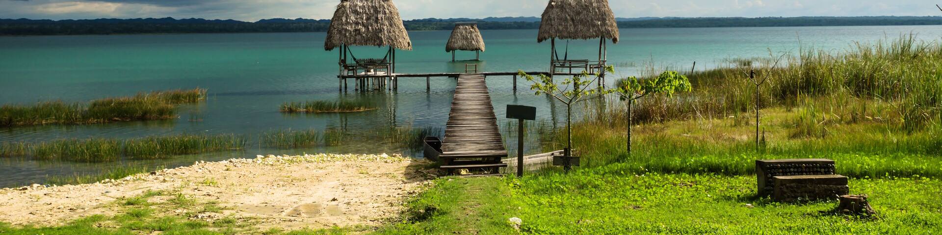 Hammocks on dock along the lake shore with dark blue cloudscape, El Remate, Peten, Guatemala