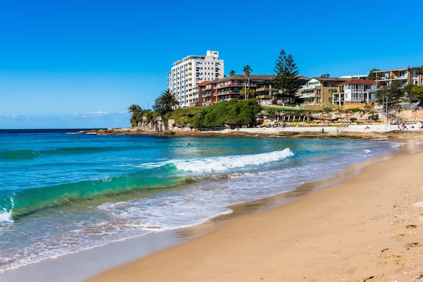 Sunny day on Cronulla beach. Urban beach with sand shore and buildings with water view. People relaxing on the background. NSW, Australia.; Shutterstock ID 328545644