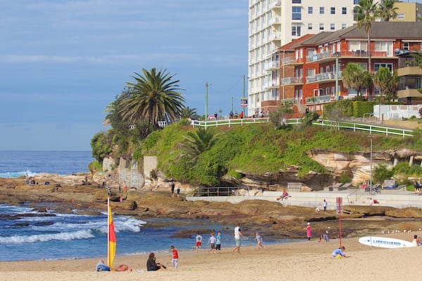 A beach with rocky shoreline, palm trees, and a lifeguard stand.