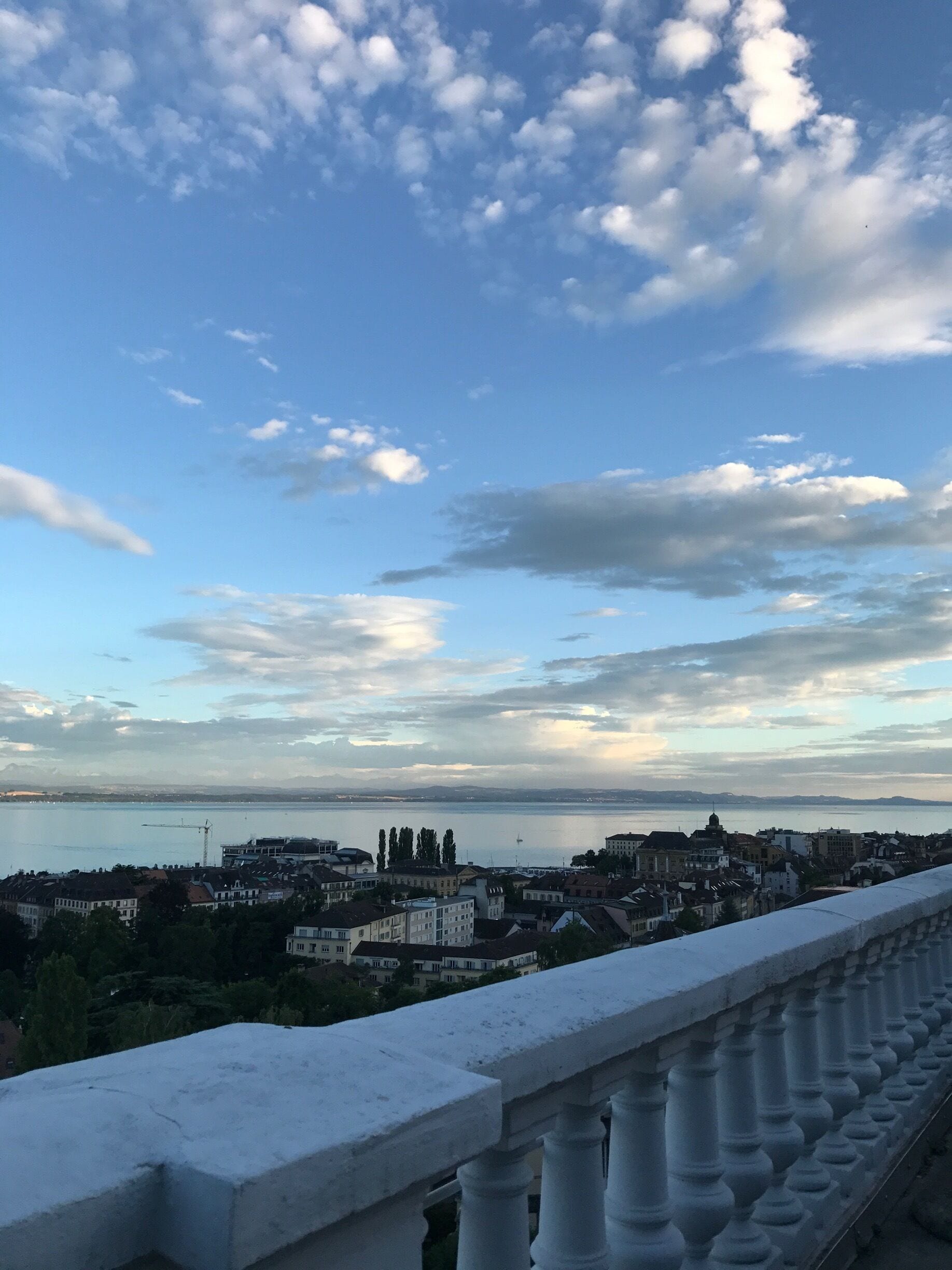A cityscape with a waterfront, buildings, and a clear sky with clouds.