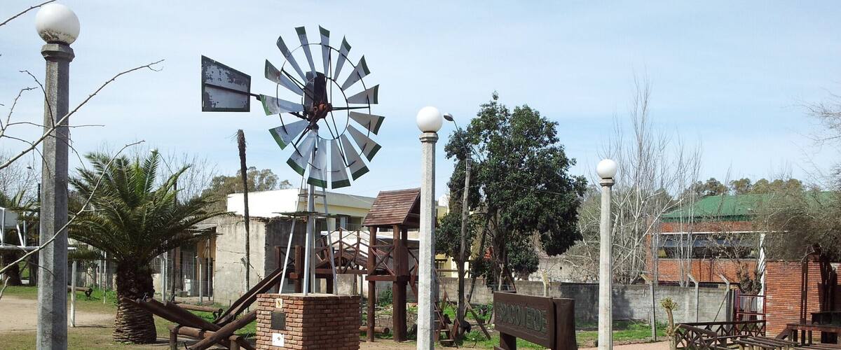 A windmill, picnic tables, and a brick structure in a park.