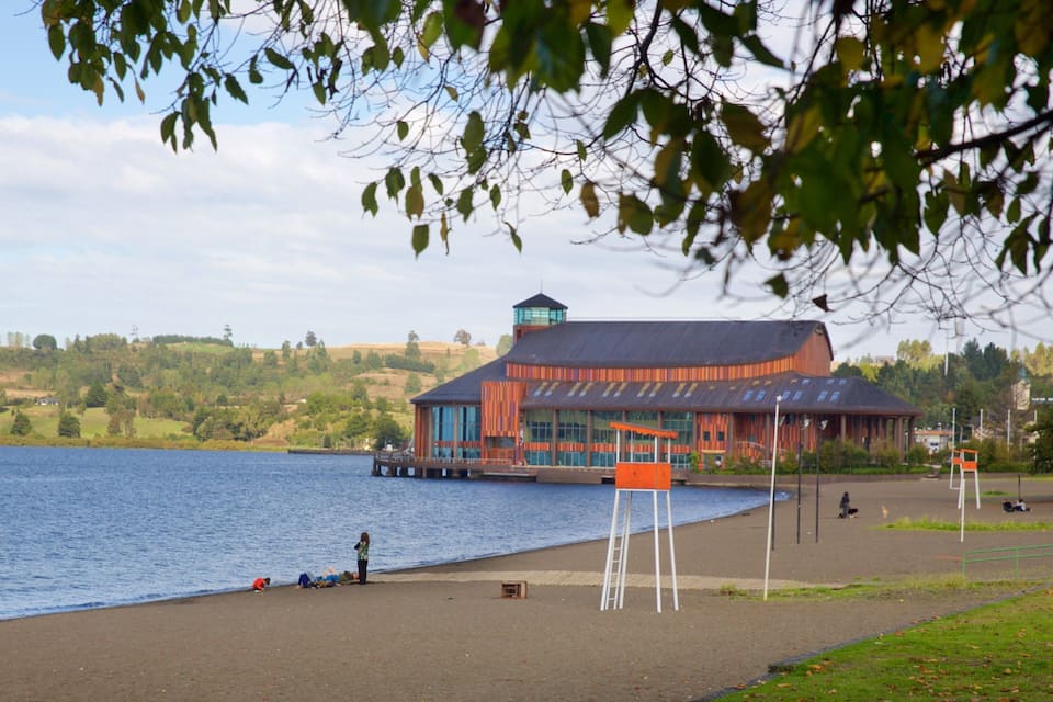 A lakeside view with a wooden building and a dock extending into the water.