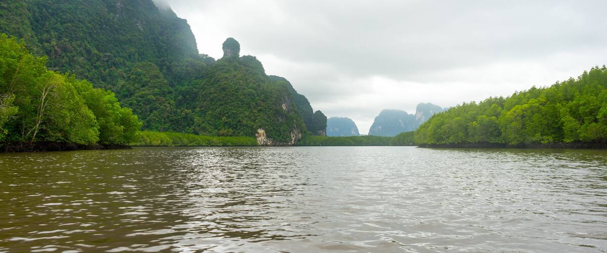A river surrounded by lush green hills and cliffs.
