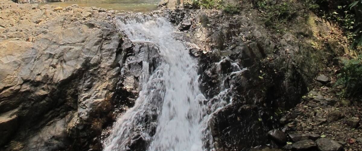 A waterfall cascading over rocky terrain surrounded by dense greenery.
