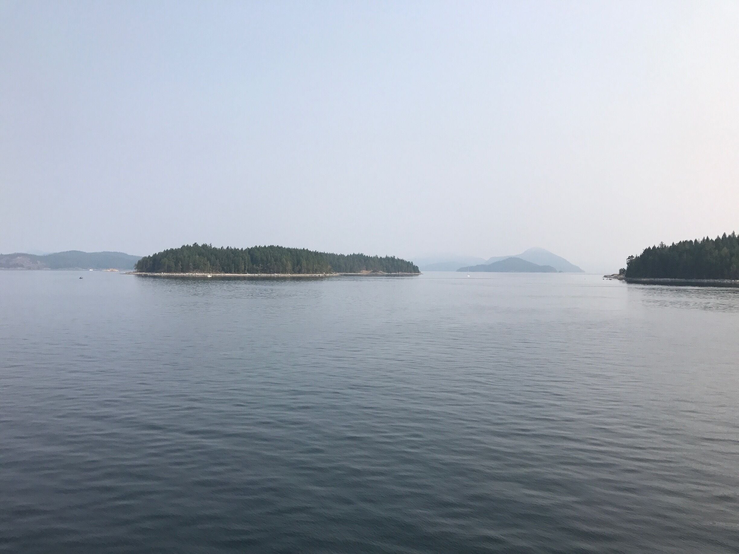 A calm lake with two small islands covered in trees.
