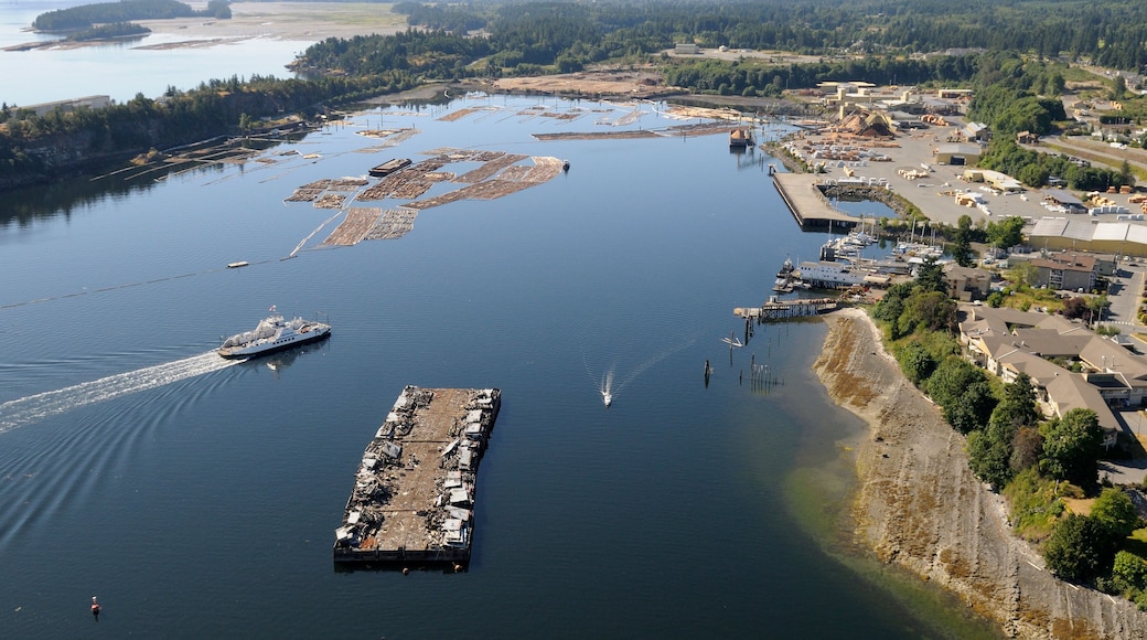 Uma área industrial costeira com uma grande extensão de água, cais e embarcações.