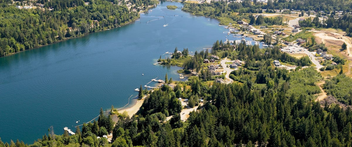 A lake surrounded by dense forests and a small town with visible buildings and docks.